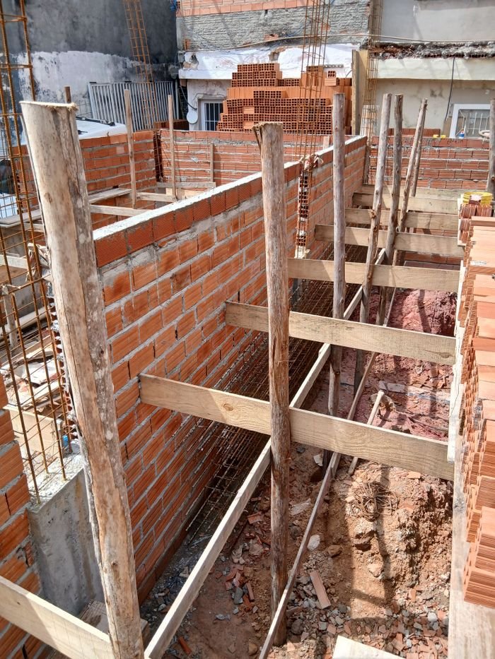 Construction site with brick walls and wooden supports under daylight.