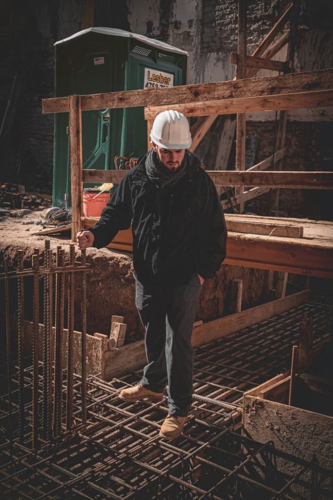 A construction worker in a hard hat inspects steel reinforcement bars on site.