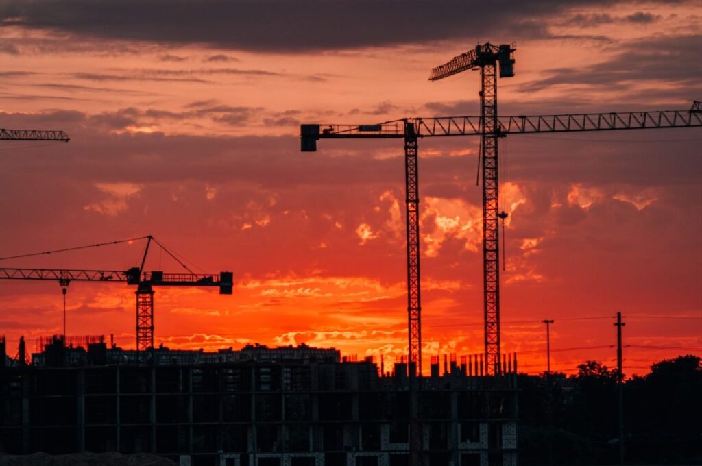 Silhouette of construction cranes against a vibrant sunset in Kaliningrad, Russia.